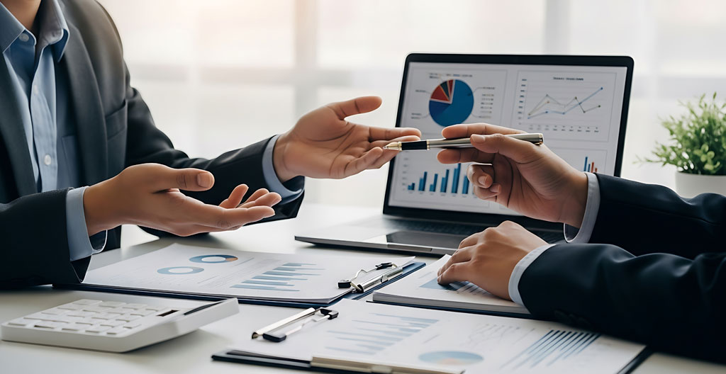 Gros plan sur des mains annotant un graphique papier avec un stylo, document financier partiellement visible en arrière-plan flouté